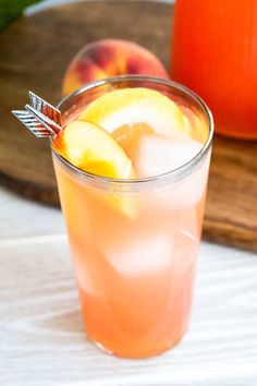 an orange drink in a glass next to some peaches