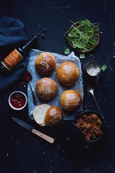 several buns on a table with condiments next to them