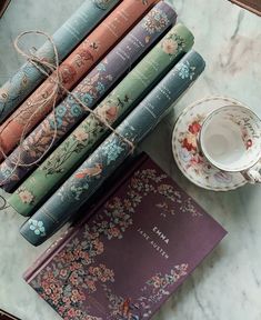 a stack of books sitting on top of a table next to a cup and saucer