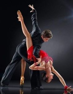 two people are performing an acrobatic dance in front of a black background