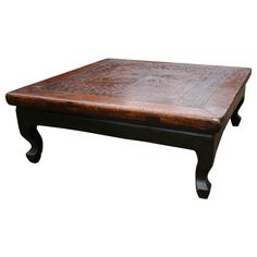 an old wooden coffee table with carvings on the top and bottom, against a white background