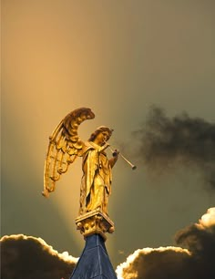 an angel statue on top of a building with cloudy skies in the backgroud