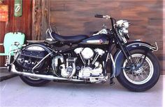 a black motorcycle parked in front of a wooden building