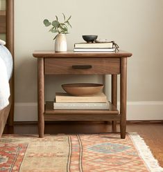 a nightstand with books and a bowl on it