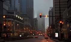 a city street with traffic lights and buildings in the background at night, as seen from across the street