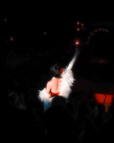 a woman with white feathers on her body in front of an audience at a concert