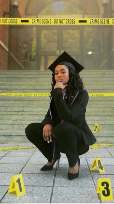 a woman sitting on the ground in front of stairs wearing a graduation cap and gown