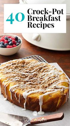 a cake sitting on top of a pan covered in icing next to berries and a knife