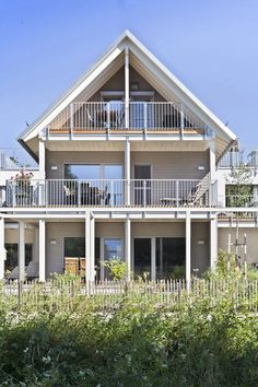 a large house sitting on the side of a lush green field next to tall grass