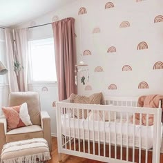 a baby's room with a white crib, pink curtains and a brown chair