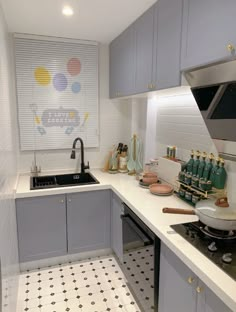 a kitchen with gray cabinets and white counter tops, black and white floor tiles and polka dot pattern on the wall