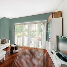 a living room filled with furniture and a flat screen tv sitting on top of a hard wood floor