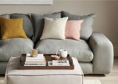 a living room with a gray couch, coffee table and two pillows on top of it