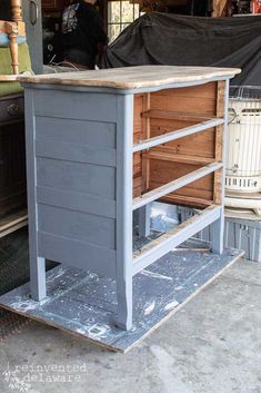 an old dresser has been painted gray and is being worked on by someone in the garage