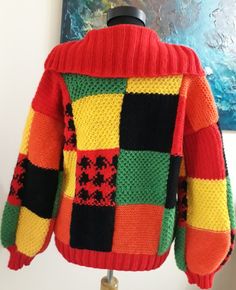 a brightly colored sweater is hanging on a coat hanger in front of a painting