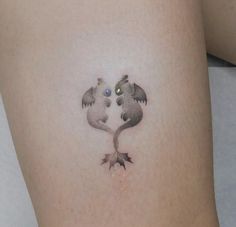 a tattoo on the side of a woman's thigh shows two birds kissing each other