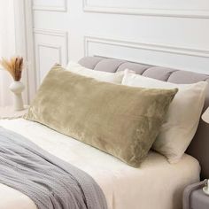 a bed with two pillows on top of it and a blanket over the headboard