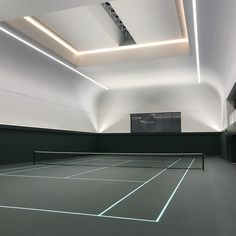 an empty tennis court with lights on the ceiling