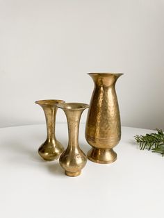 three brass vases sitting next to each other on a table