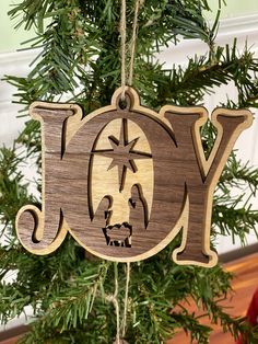 a wooden ornament with the word joy hanging from a christmas tree in front of a window