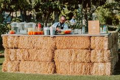 a man sitting at a bar made out of hay bales with drinks on it