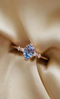 an engagement ring with a blue topazte surrounded by diamonds on a satin background