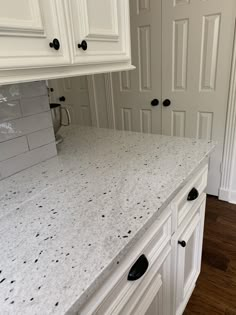 a kitchen with white cabinets and marble counter tops