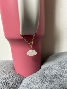 a pink vase with a gold chain attached to it and a white cloud charm hanging from the side