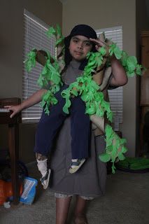 a woman holding a child in her arms with green leaves on it's back