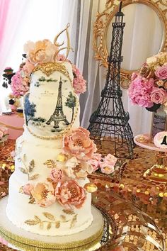 a three tiered cake decorated with flowers and the eiffel tower in the background