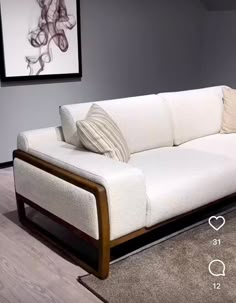 a white couch sitting on top of a hard wood floor next to a painting and rug