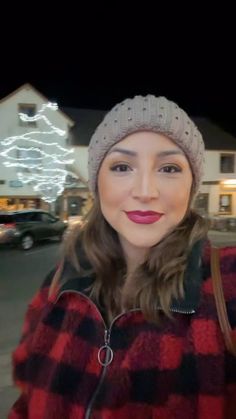 a woman wearing a red and black plaid coat is taking a selfie with her cell phone