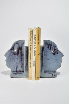 two bookends made out of metal with books on each side and one in the shape of a head