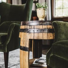 a wooden table with a potted plant sitting on it's top next to two green chairs