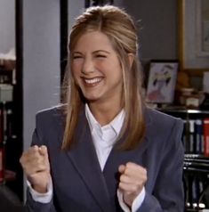 a woman in a suit is smiling and raising her fist