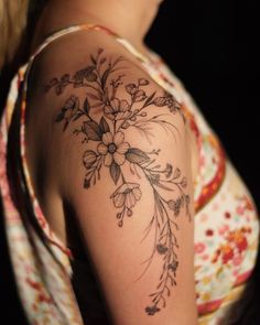 a woman with a flower tattoo on her arm and shoulder is looking away from the camera