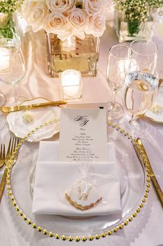 the table is set with white flowers and gold place settings