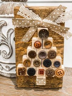 a christmas tree made out of buttons on top of a wooden block with a ribbon