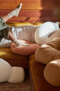 a woman laying on top of a couch next to pillows and stuffed animals in front of her