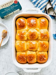 rolls in a baking dish with butter and honey on the side, next to a box of butter