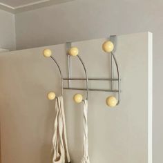 a wall mounted coat rack with three balls on it and two hooks hanging from the ceiling