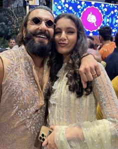 a man and woman pose for a photo in front of a crowd at an event