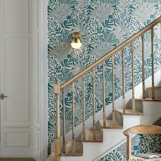 a stair case in front of a wall with black and white designs on it, next to a wooden chair