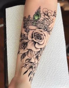 a woman's arm with flowers and a crown on it