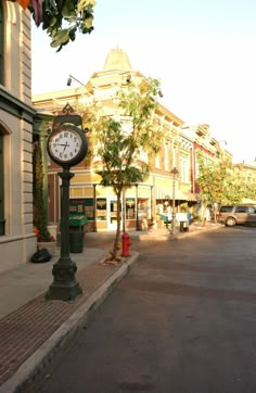 a clock sitting on the side of a street