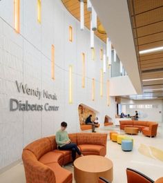 a man sitting on an orange couch in a lobby