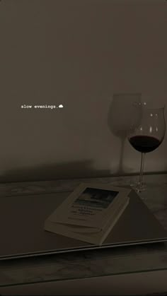 a glass of wine sitting on top of a table next to a book and tablet