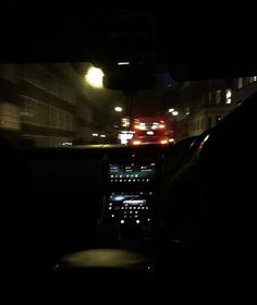 the interior of a car at night with street lights and buildings lit up in the background