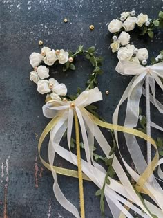 two white roses tied with ribbons and some other flowers on the ground next to each other