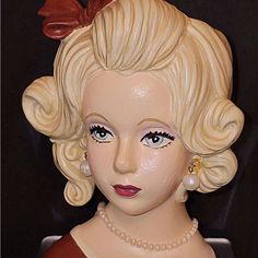 a close up of a statue of a woman with blonde hair and pearls on her head